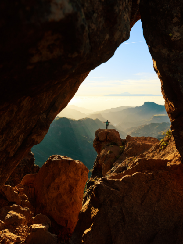 A person standing on a rock in sunshine surrounded by a canyon